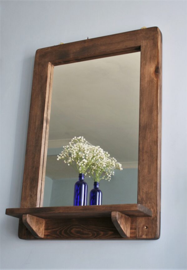 Wooden mirror with candle shelf in portrait, seen from below.