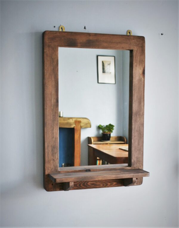 Wooden mirror with shelf in portrait with empty shelf.