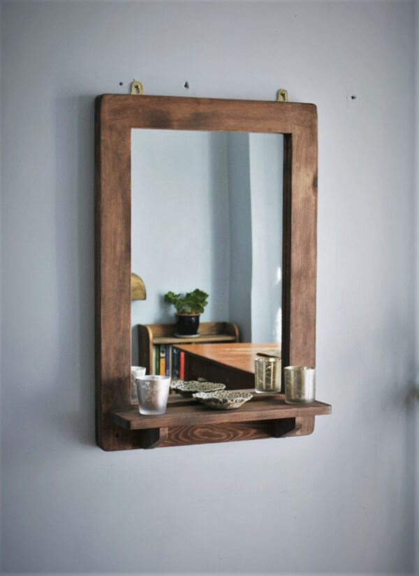 Wooden mirror with candle shelf in portrait.