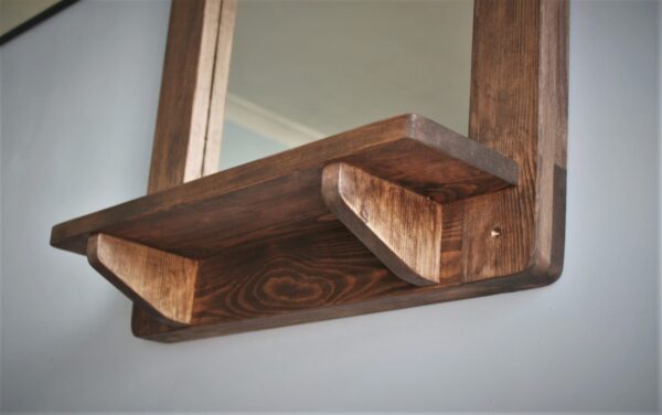 Wooden mirror with candle shelf in portrait, close up of underneath the shelf.
