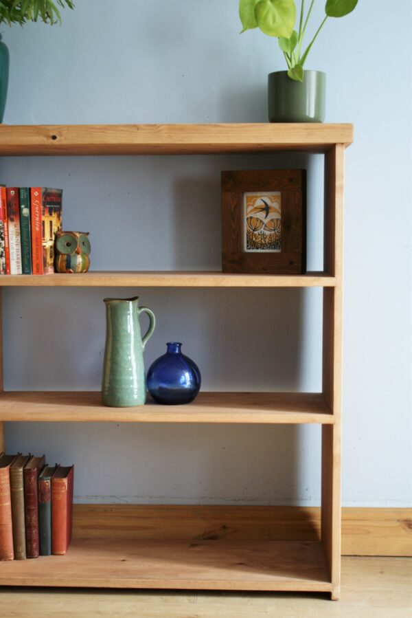 Wide wooden bookshelves in chunky rustic natural wood, handmade in Somerset UK. Side close up view.