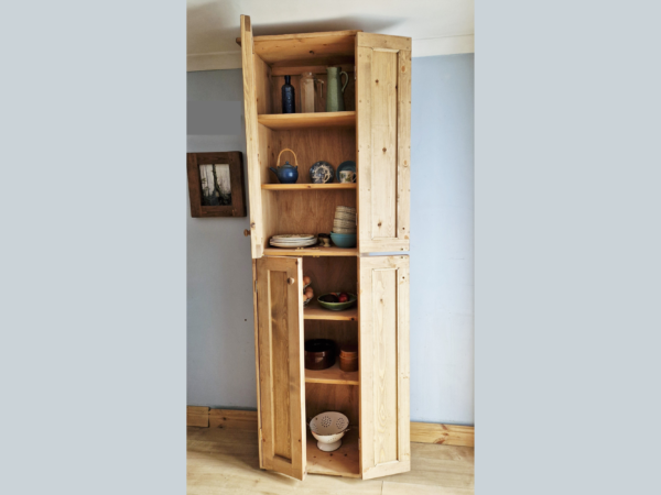 Tall kitchen larder pantry cabinet in natural wood with doors open.