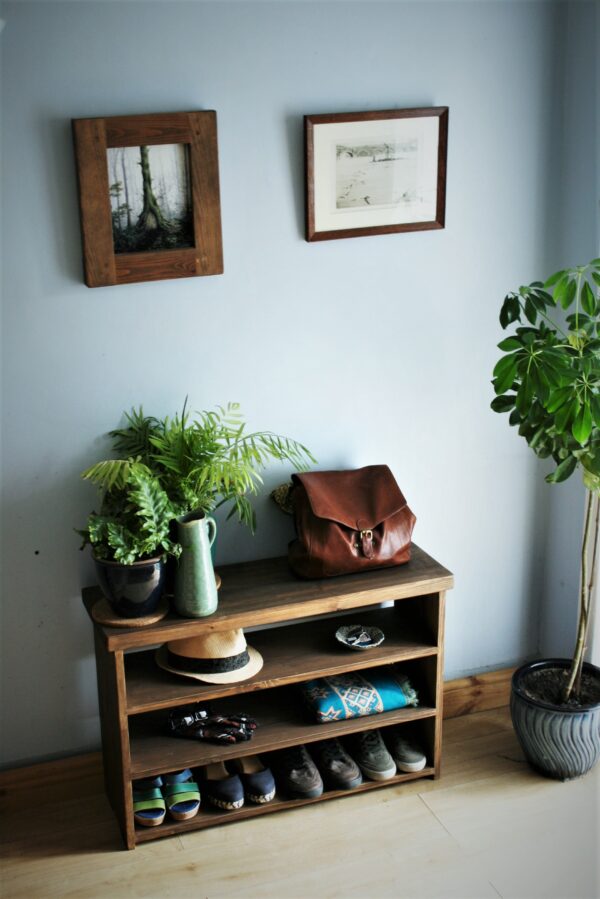 Rustic shoe rack bench and hall table in natural wood, with handbag and plants.