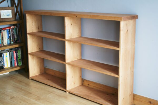 Wide wooden bookshelves in chunky rustic natural wood, handmade in Somerset UK. Empty of books.