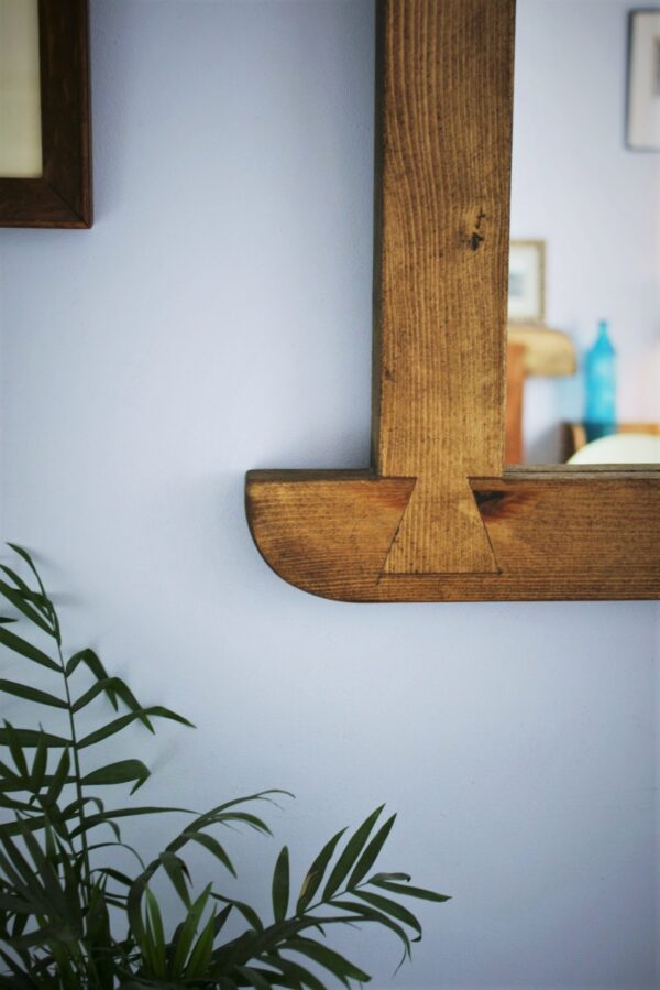 Arched mirror in dark wood, close up of dovetail decoration.