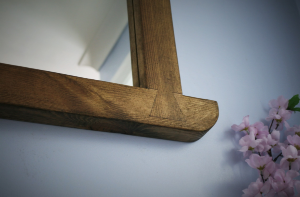 Arched mirror in dark wood, close up of lower dovetail decoration.