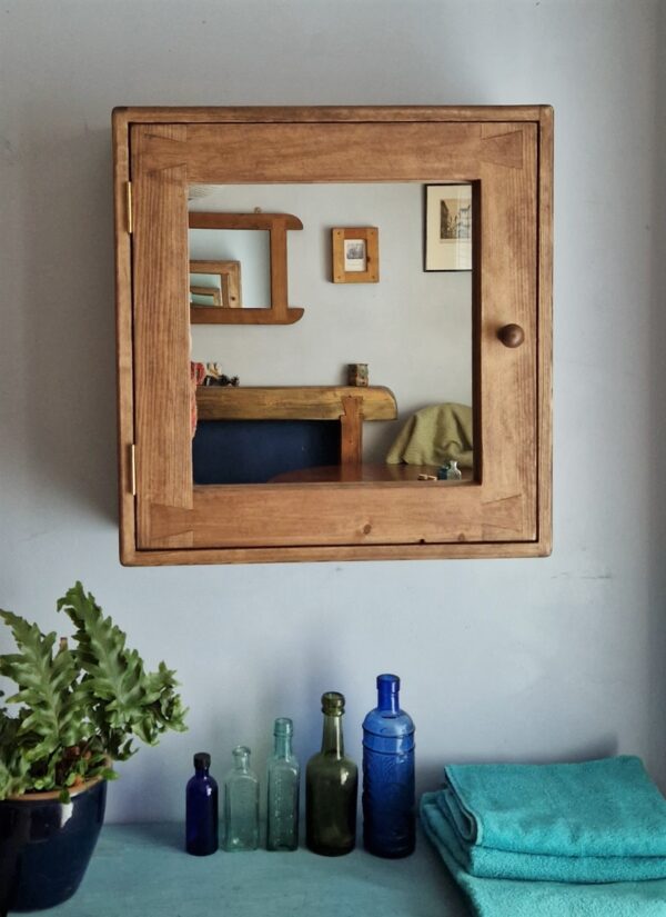 Large wooden bathroom cabinet with mirrored door and round wooden handle. Handmade in dark wood from rustic Somerset UK
