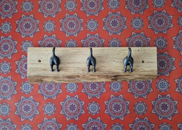 Live edge coat rack with 3 ‘waggy dog tails’ cast iron hooks on a chunky natural Oak plaque, retro wallpaper.