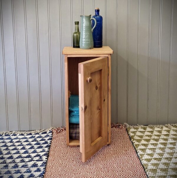 Floor standing bathroom cabinet, slim modern rustic wooden storage cupboard, with chunky panel door open, UK